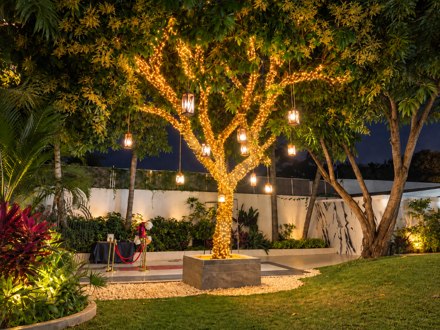 Árbol iluminado con series de luces y faroles colgantes en el jardín de Allegra 55, Cuernavaca