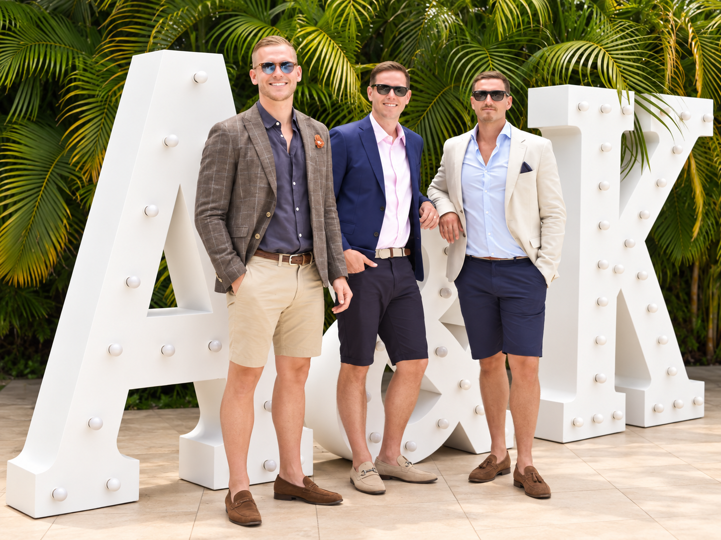 Invitados internacionales posando junto a letras iluminadas blancas en una boda en Jardín Allegra 55, Cuernavaca