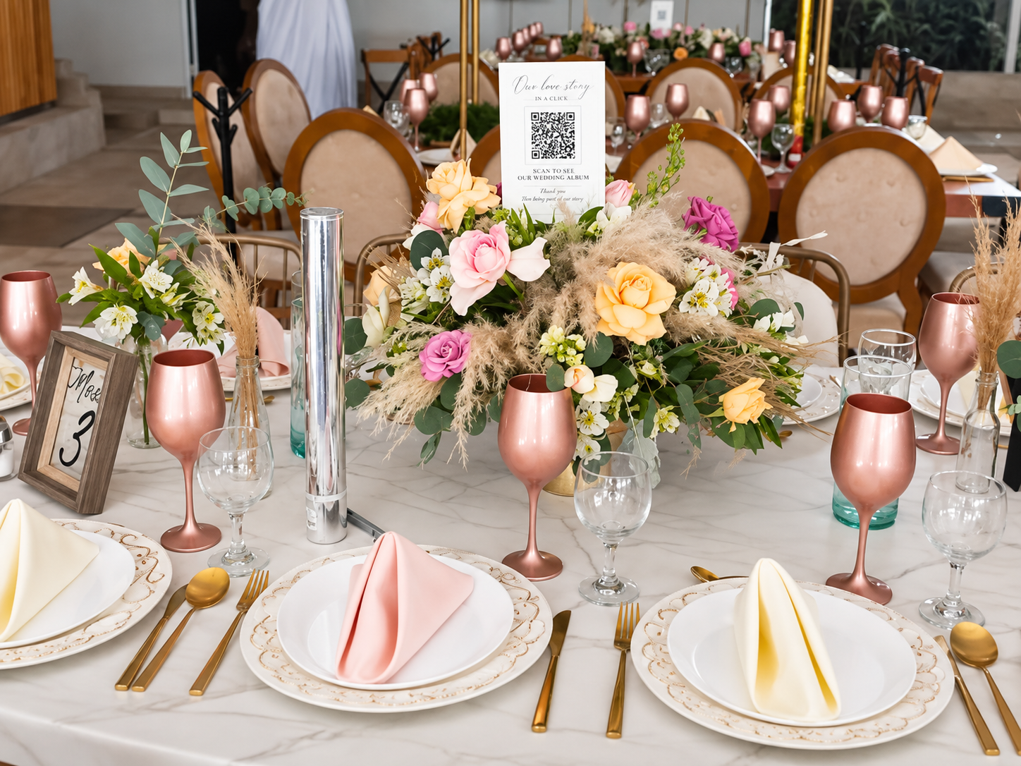 Mesa con copas rosa gold, centro de mesa floral y código QR del álbum de boda en Jardín Allegra 55, Cuernavaca