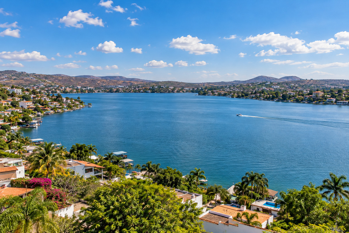 Panoramic view of Lake Tequesquitengo, Morelos, with lakeside houses and a boat on the water.