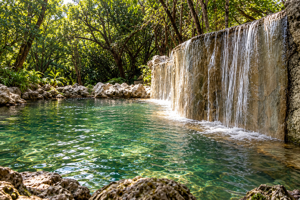 Water flowing over rock into a pool surrounded by trees at Los Manantiales, Coaxitlán, Morelos.