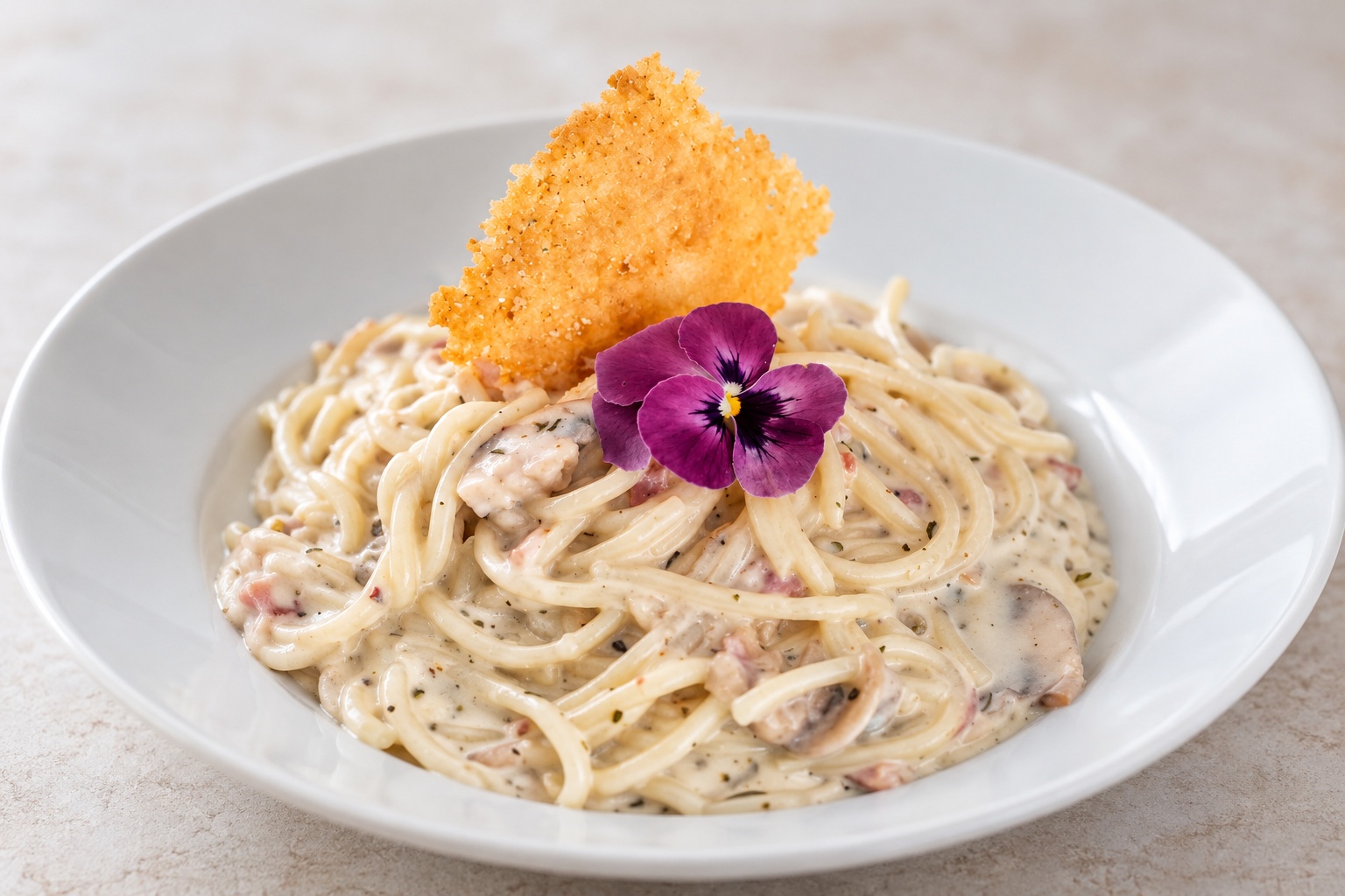 Pasta larga en salsa cremosa con champiñones, decorada con un crujiente dorado y una flor morada sobre un plato blanco.